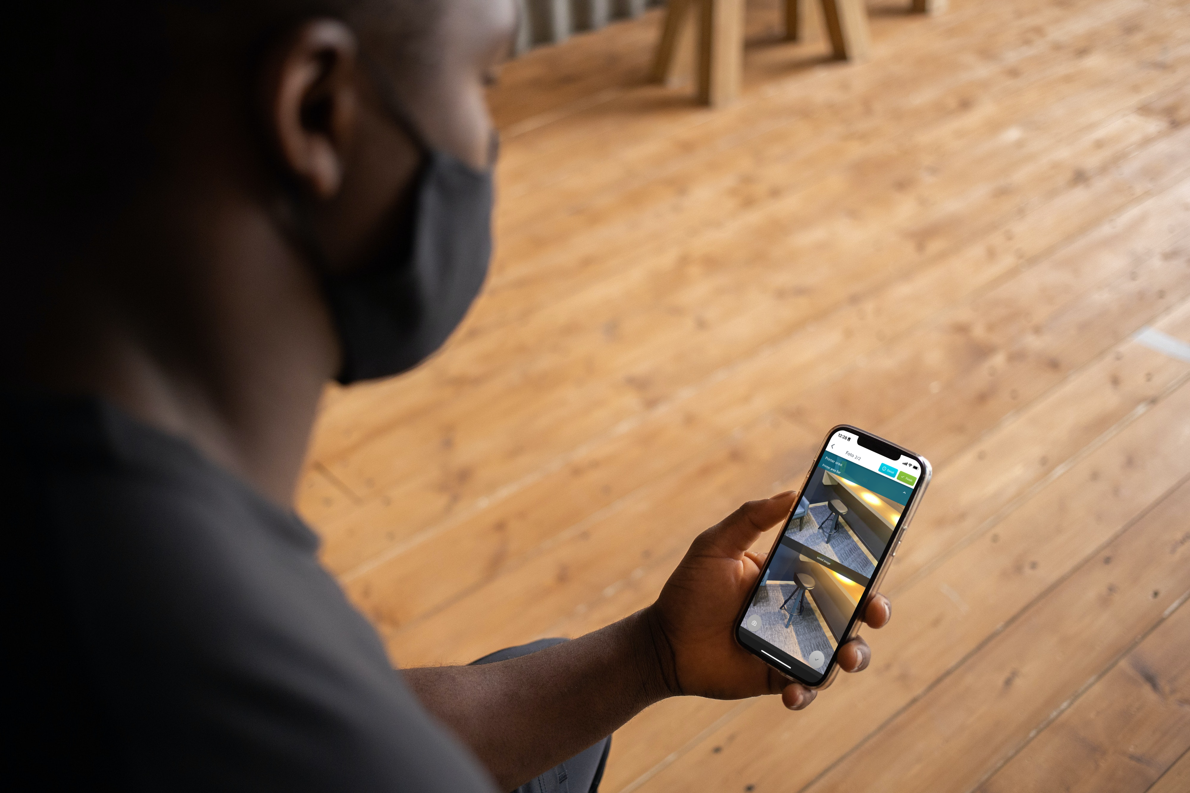Cleaning staff holding a smartphone and using the FotoFinish mobile app to capture a photo report on-site